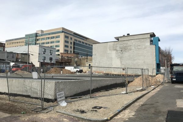 Lote urbano cercado en obra, con los muros de cimentación en concreto ya vaciados, la excavación abierta y montículos de tierra extraída alrededor.