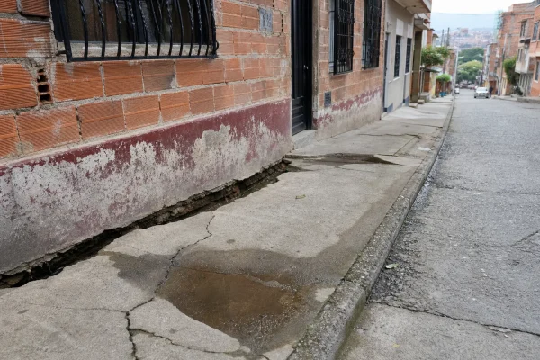 Andén hundido y separado de la fachada de una casa de ladrillo en un barrio de Medellín